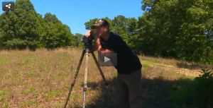 Adam leaning on a camera tripod