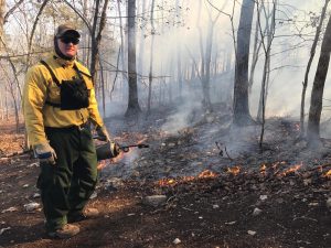 Tyler working a prescribed fire, holding a drip torch