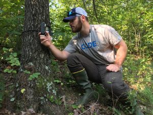 A hunter wears rubber boots when checking a Reconyx trail camera to help minimize scent