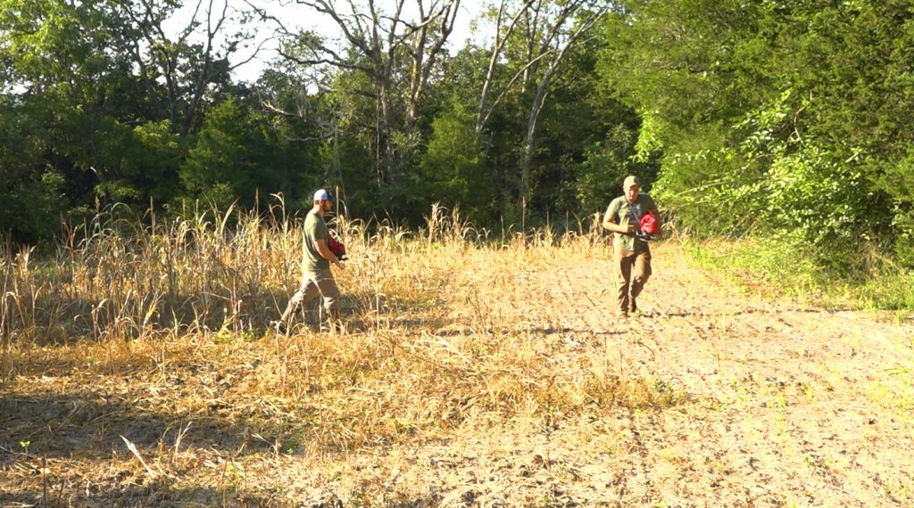 two young men broadcasting food plot seed