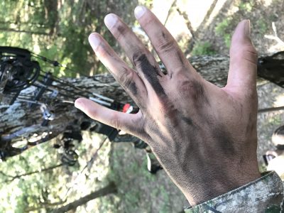 A hunter uses black face paint on his hands.