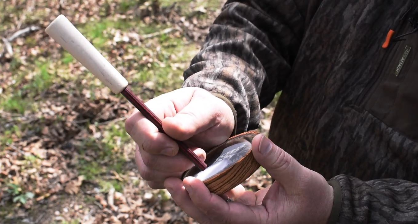 Hands holding a glass pot call for turkey hunting