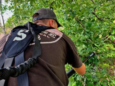 a hunter uses an extendable saw to trim growth from around a tree stand