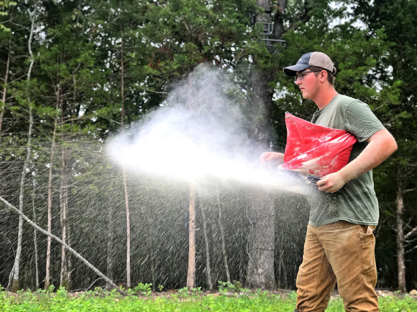 Owen Zimmer using a hand spreader to plant a food plot